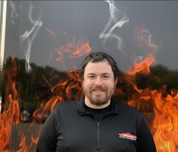 Nick, male job file coordinator. Standing against a fake fire backdrop