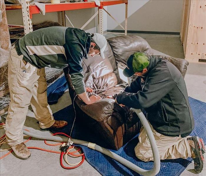 Two SERVPRO employees cleaning a damaged sofa